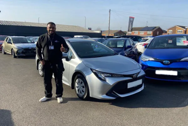 successful car sourcing for a customer, customer standing by his new car
