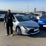successful car sourcing for a customer, customer standing by his new car